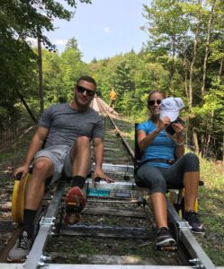 Picture of a man and a woman peddling a railcar in the wilderness.